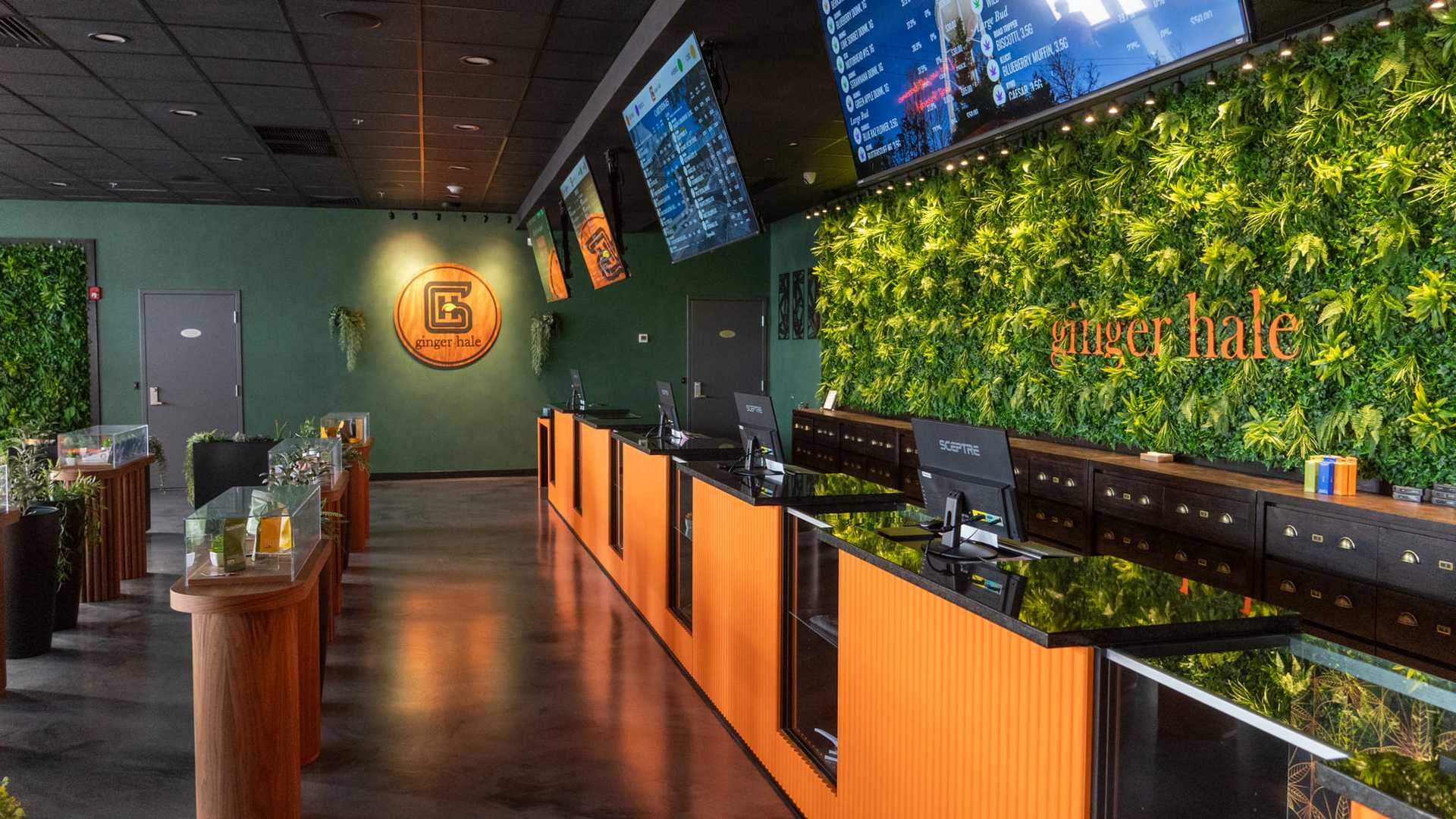 Modern cannabis dispensary with green wall, illuminated counters, and digital menus displayed.
