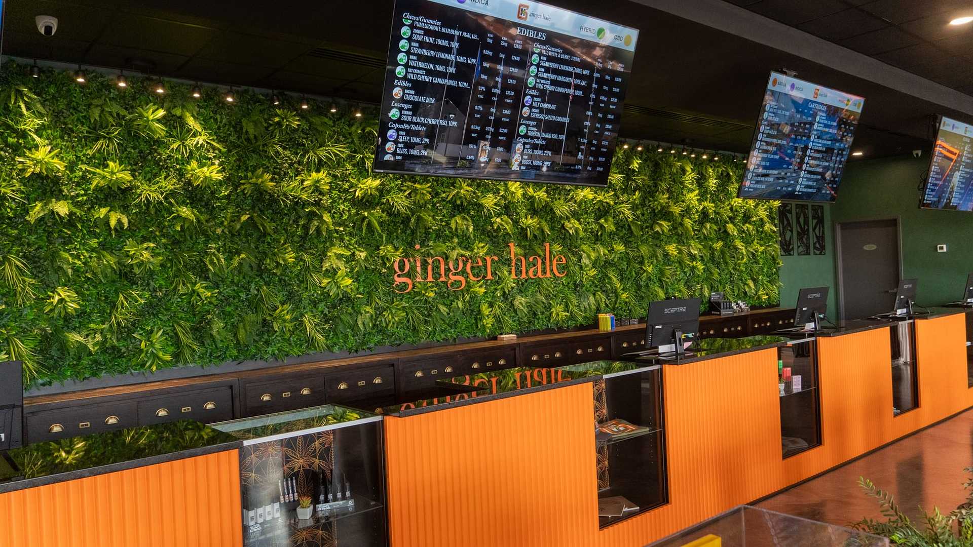 Modern restaurant interior with green plant wall, digital menus, and "ginger hale" sign.